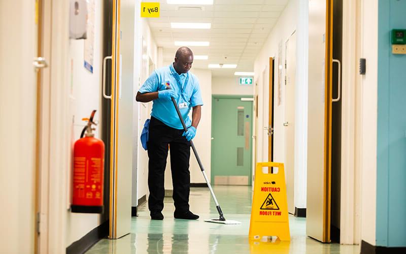 Mitie hospital cleaner mopping the floor in a corridor