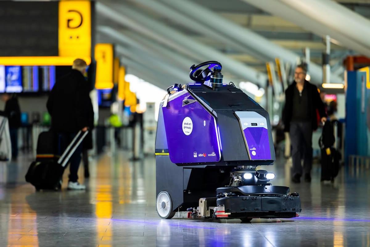 Mitie robotic cleaner, clad in purple, automatically patrolling in Heathrow Airport